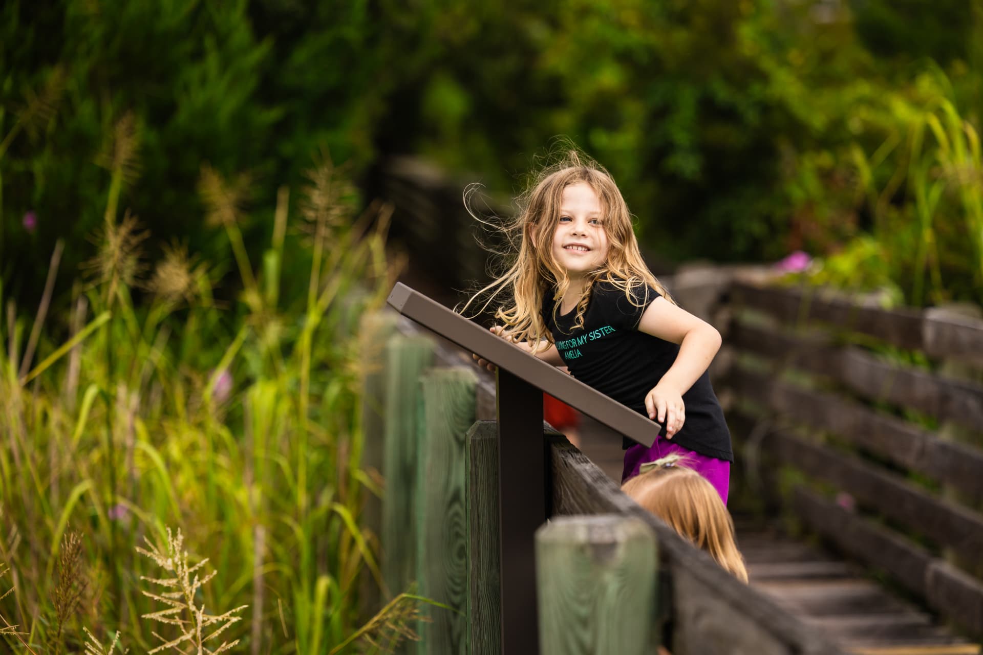A girl smiling on a marsh boardwalk overlook