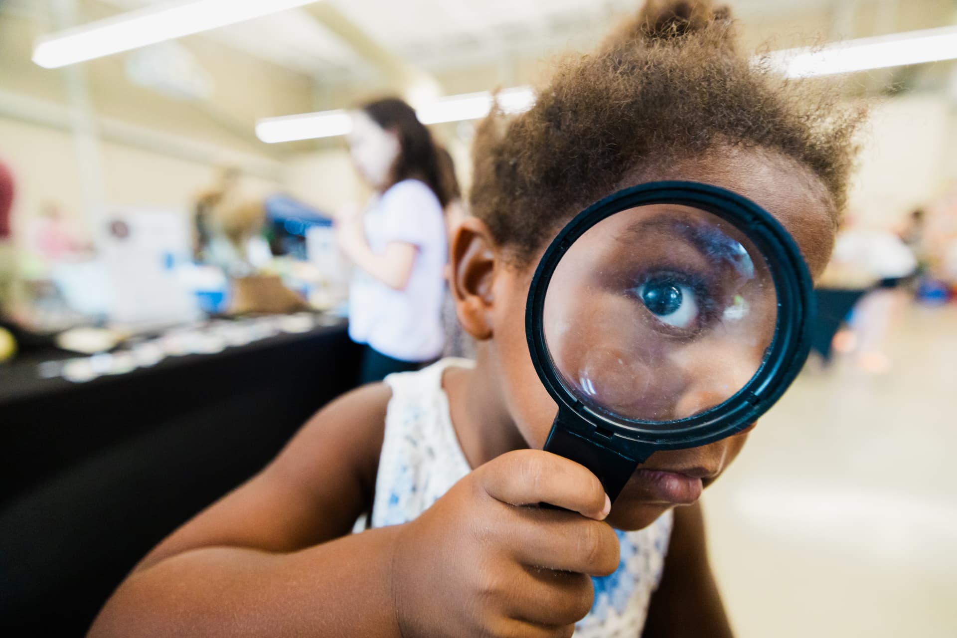 A child looking through a magnifying glass at a Sturgeon City science event