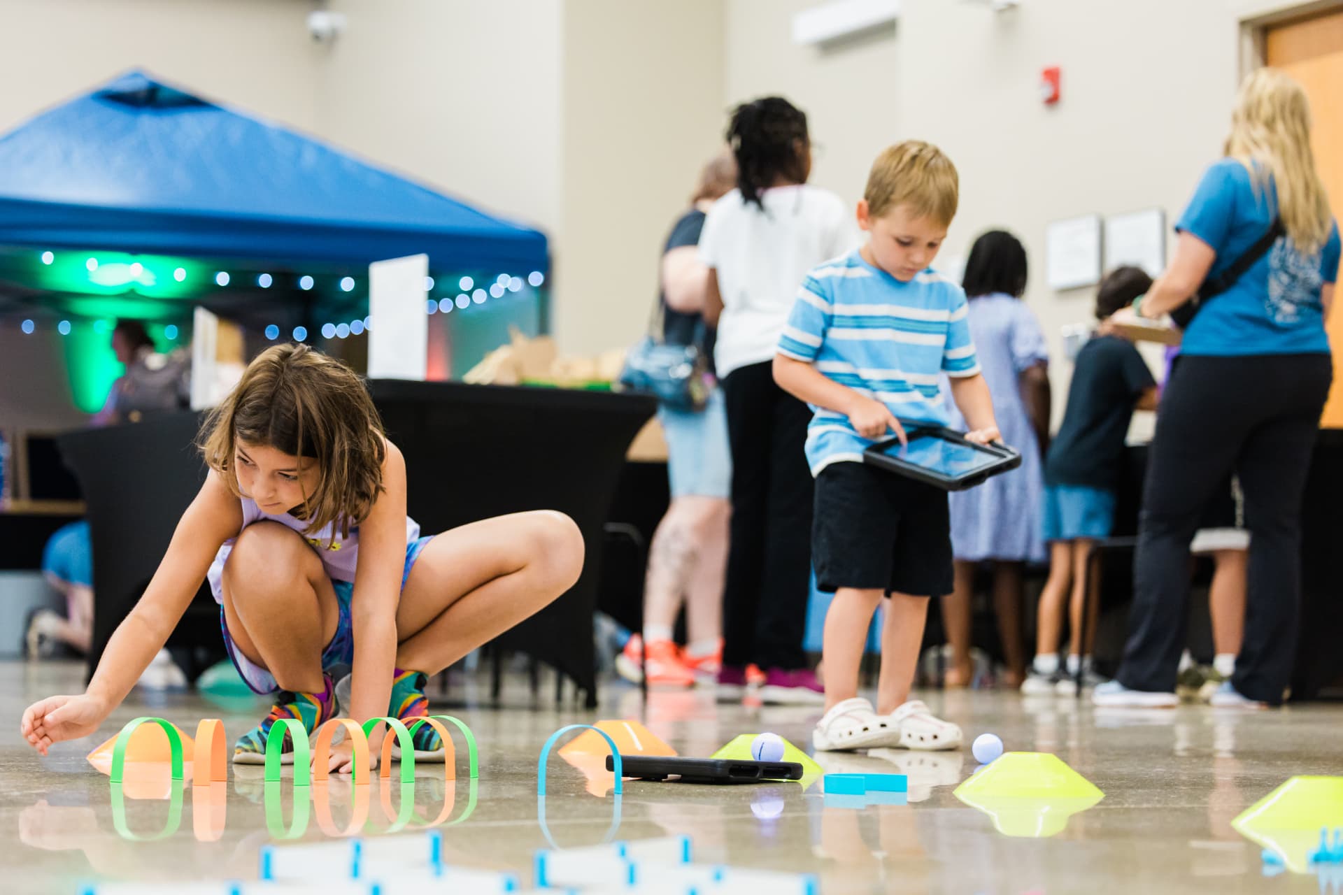 Children guiding a coding robot through a course at a STEAM event